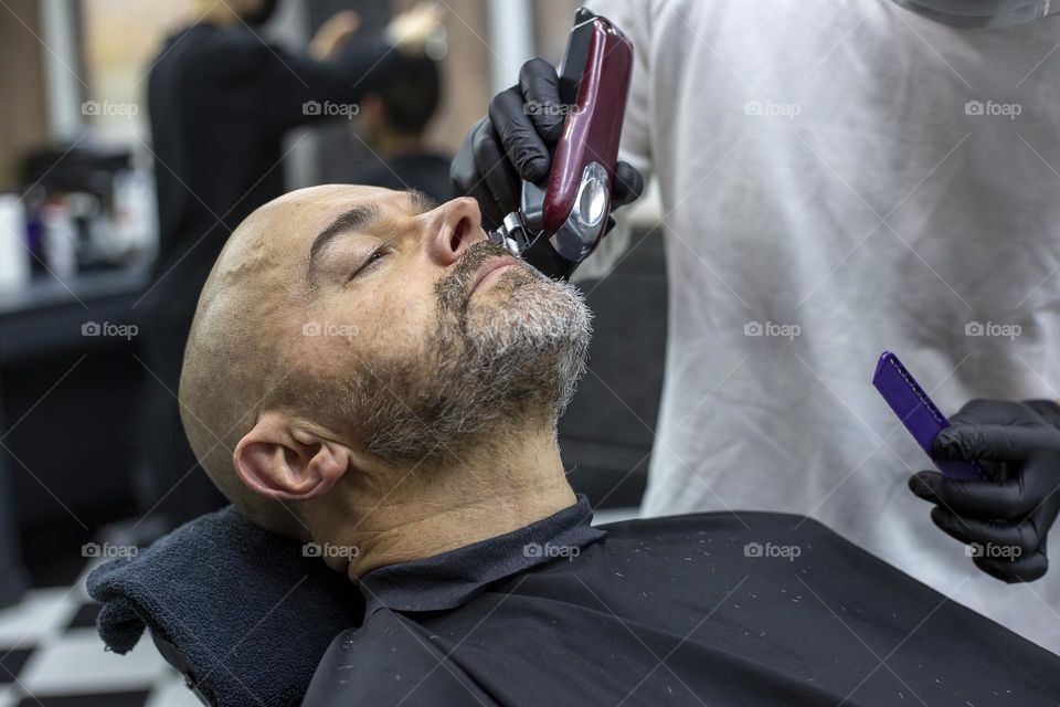 Man having beard trimming in the barbershop 