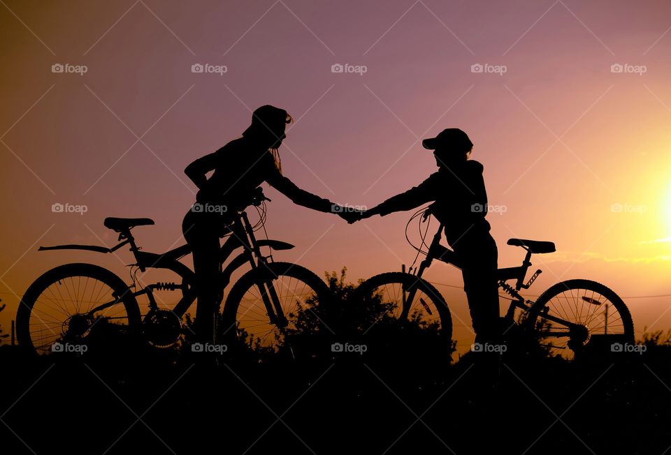 Silhouette of a boy and a girl on bicycles.