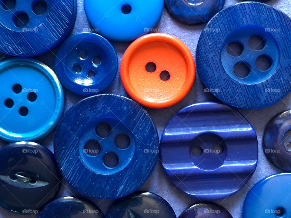 A collection of blue buttons with one orange button