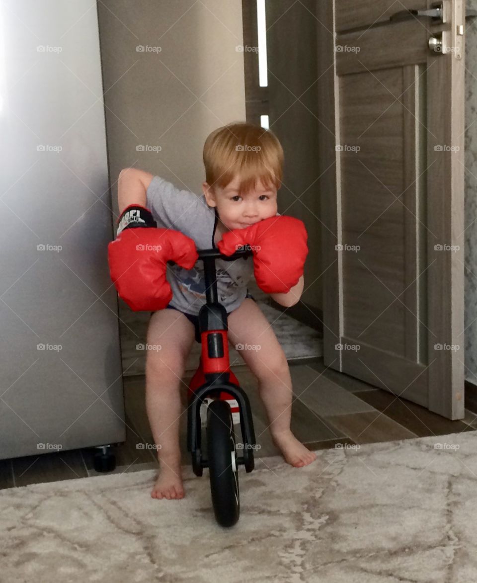boy with boxing gloves on the balance bike