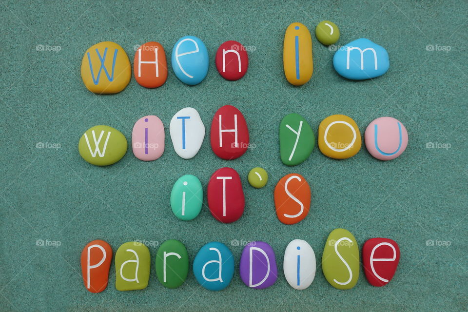 When I'm with you, it's paradise, love message composed with multi colored sea stones over green sand