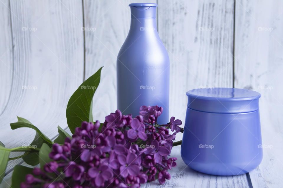 Spring, purple fragrant lilac with green leaves.  and jars with cosmetic cream and product.