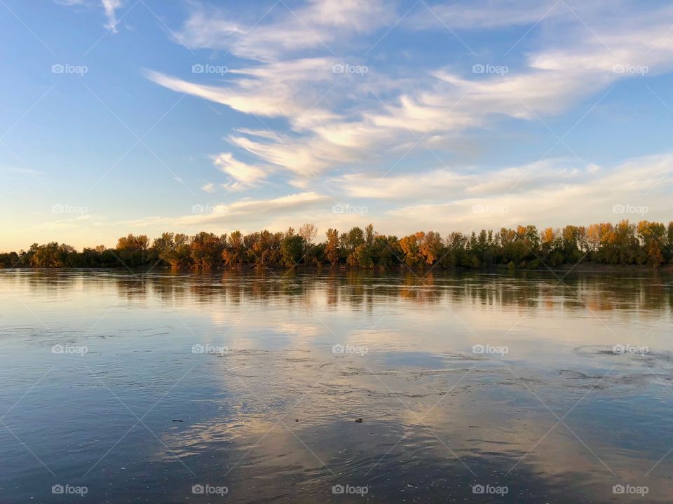 At the edge of the river as the sun goes down during autumn.
