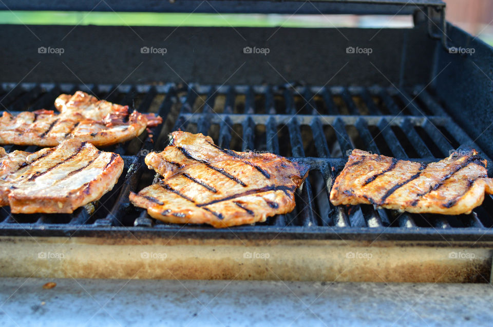 Pork chops cooking on a grill