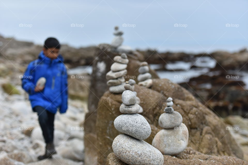 Child dismantling rock stacks built by tourists on beach