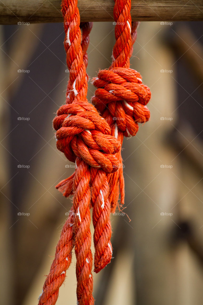 Orange! Macro image of a dark orange knotted rope hanging off a rail