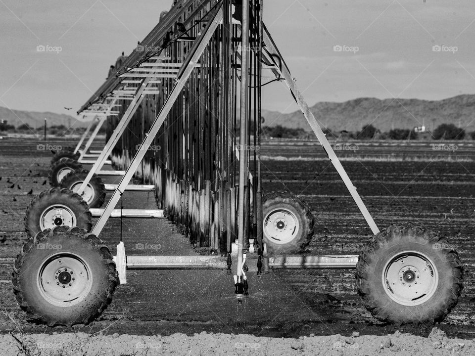 A closeup view of a massive irrigation device that sprays water on an arid and barren field which will soon sprout cotton