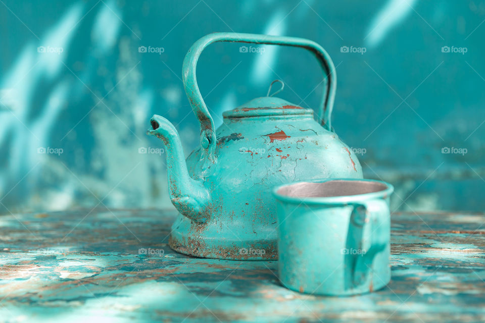 An old antique turquoise tea pot and tin mug