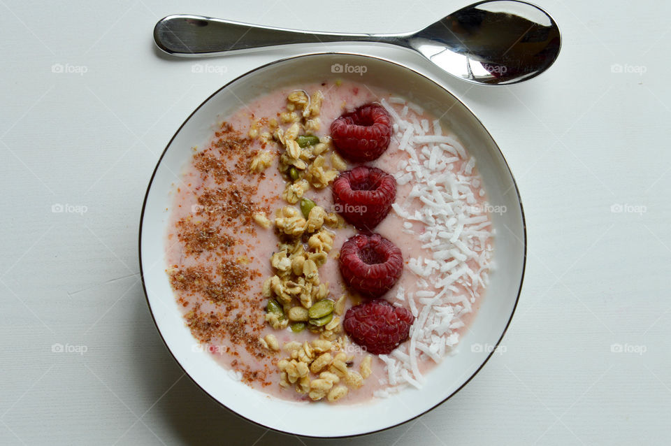 Fresh fruit smoothie bowl with flaxseed, granola, raspberries, and coconut shavings