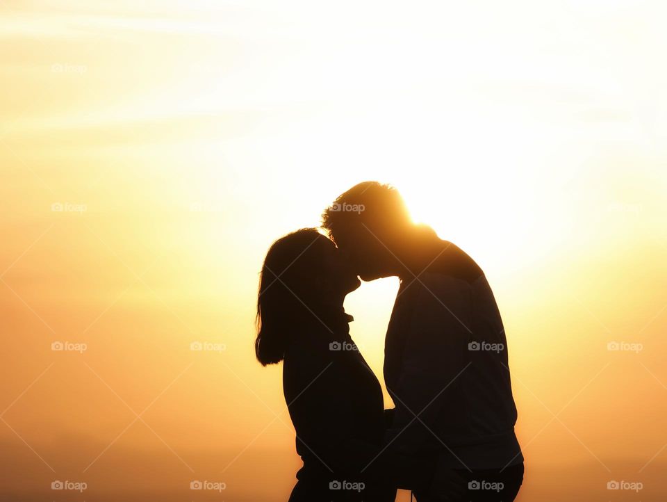 silhouette of couple kissing at sunset