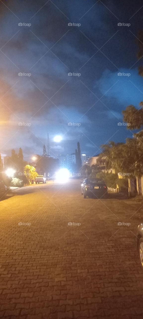 Moon and street lights creating illusion of many moons with one releasing brilliant light on the ground