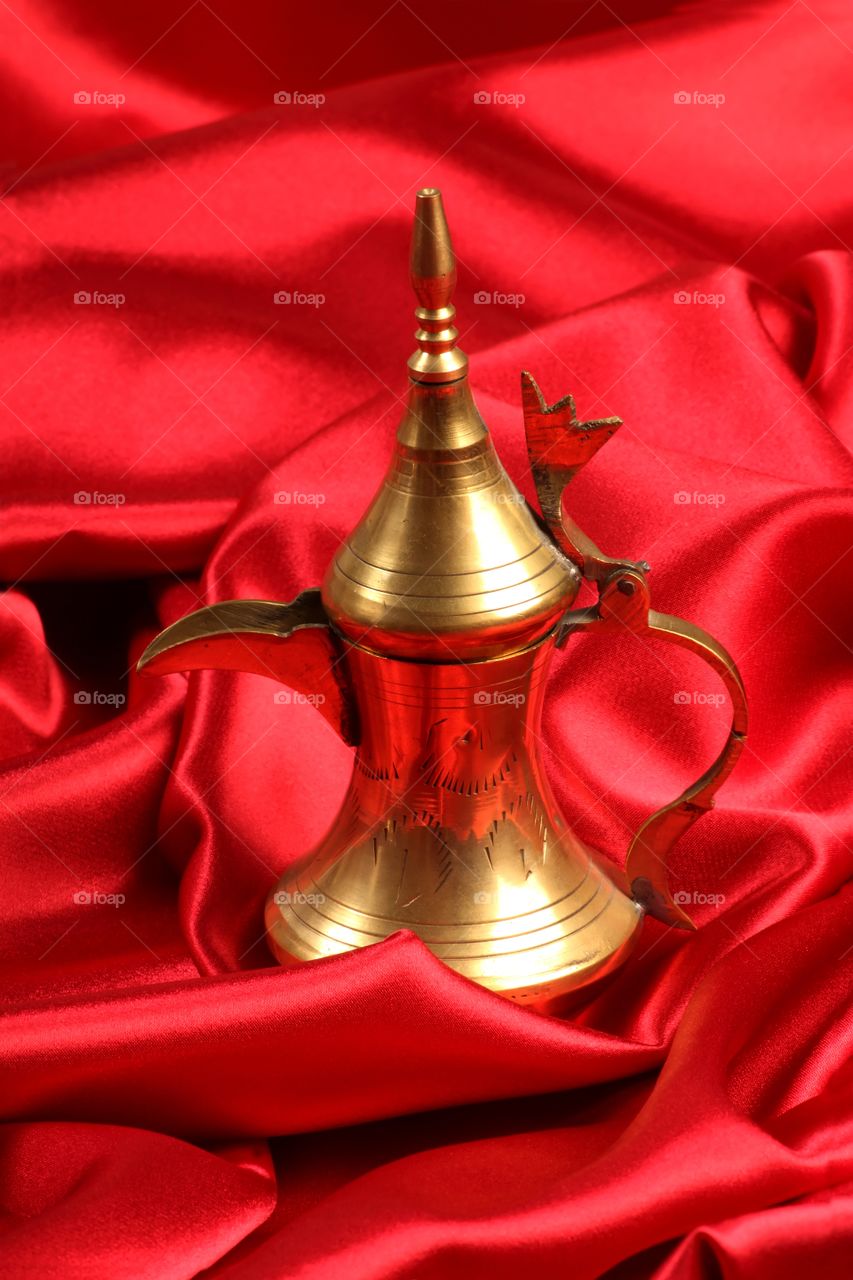 Arabic coffee pot Dallah on red satin background