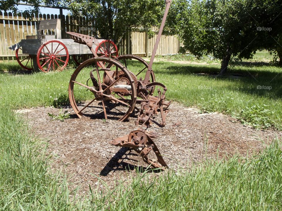 A rusted old field plow being used as an ornamental garden decoration in Central Oregon on a sunny summer day. 