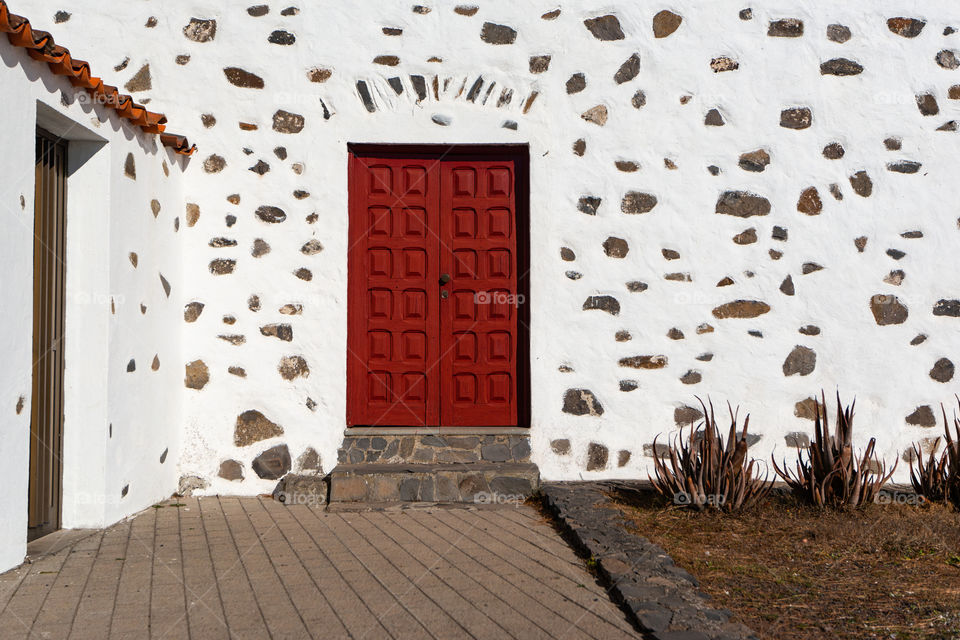 Red door against a white stone wall.