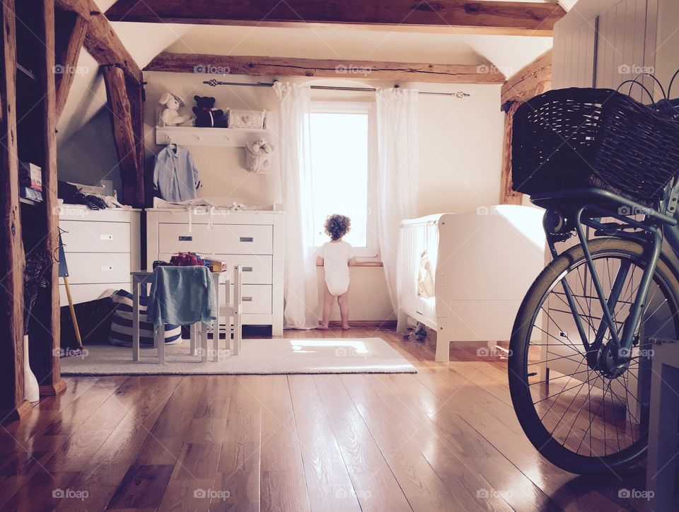 Lovely Boy looking though the window. Boy in the attic