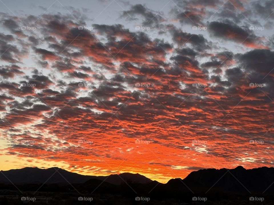 A photo of a sunset with bright red clouds above mountains. 