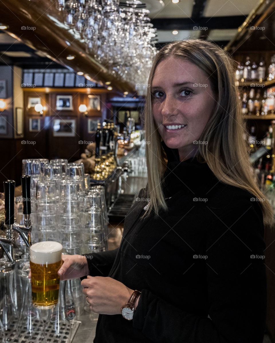 Woman Bartender tap up a beer