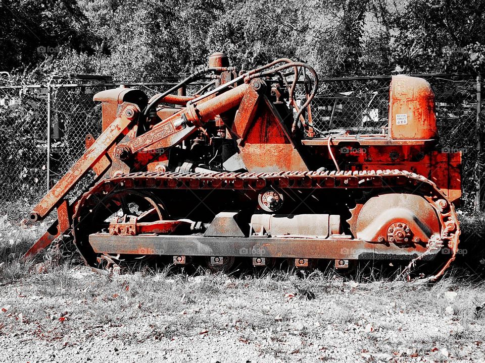 A colorized tractor in an abandoned field illustrates the rust and corrosion that is present