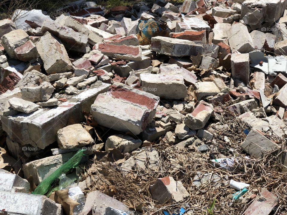 Pile of bricks and rubble outside by the side of the road.