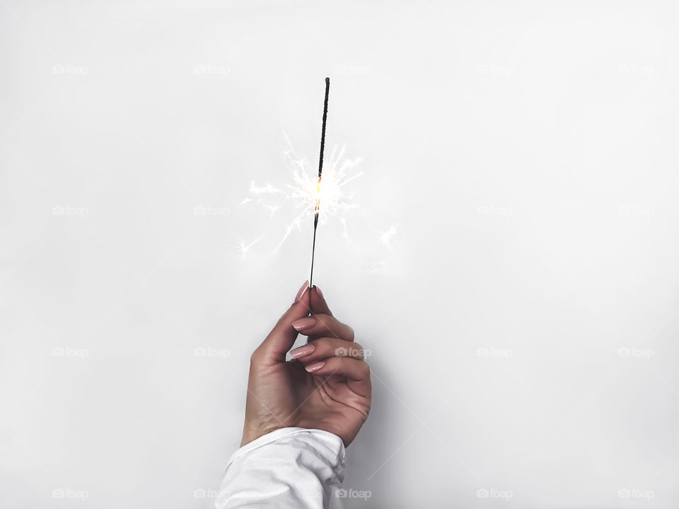 Female hand holding sparkles on white background 