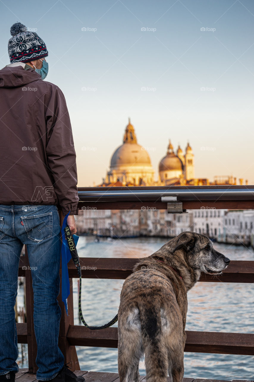 Portrait of man with dog against monumental buildings in canal of Venice, Italy
