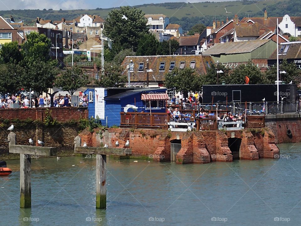 Tourists enjoy a sunny summer day along the bay while on vacation in Folkestone in England 