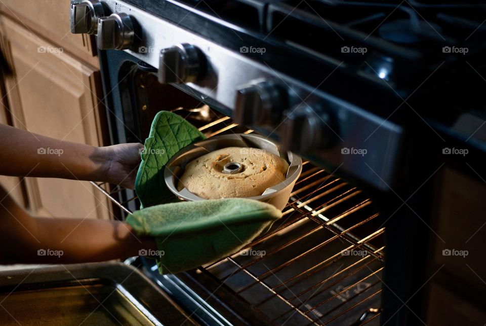 Freshly baked Bundt cake being taken out from an oven 