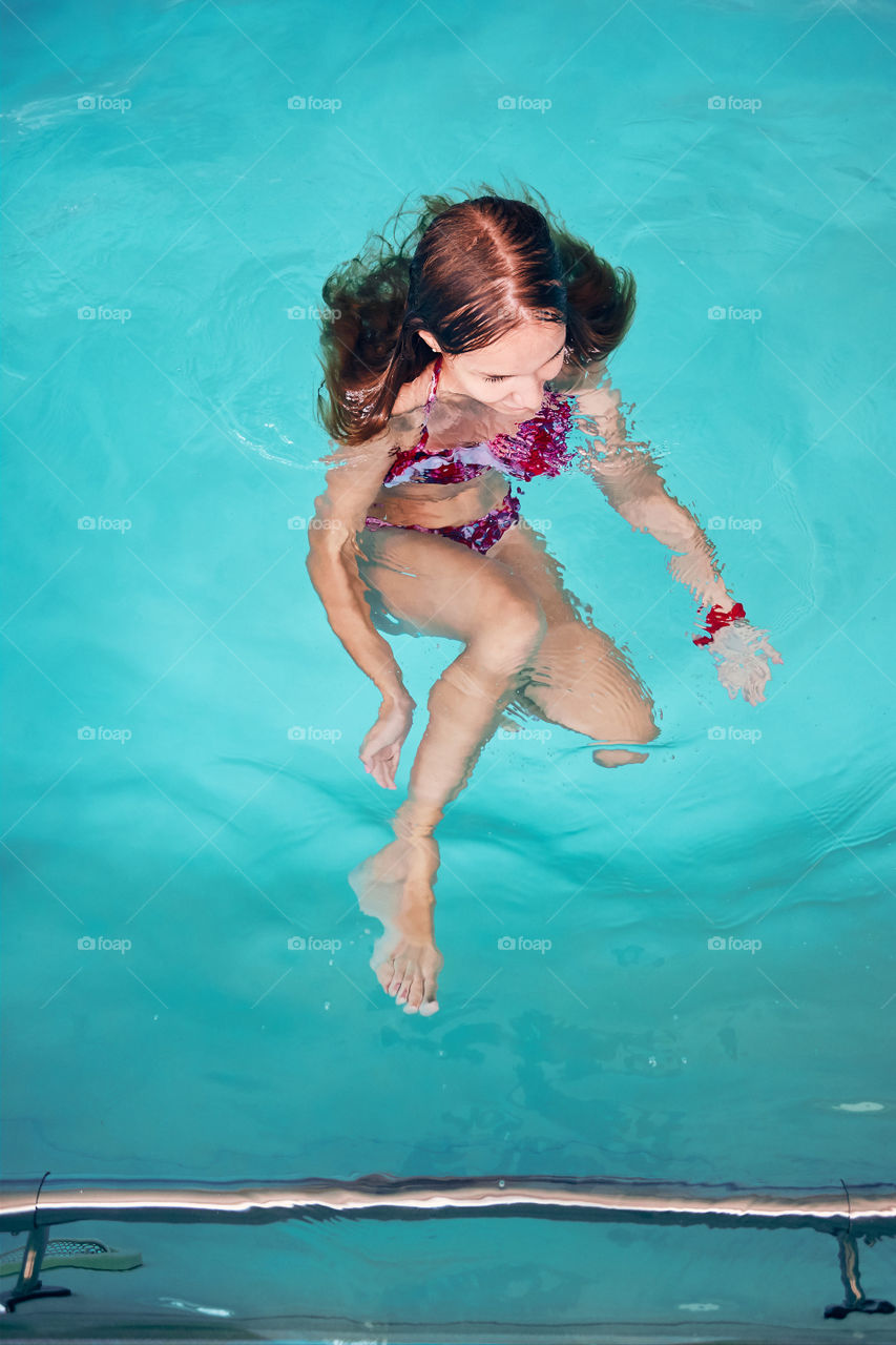 Young woman swimming and relaxing in swimming pool. Candid people, real moments, authentic situations