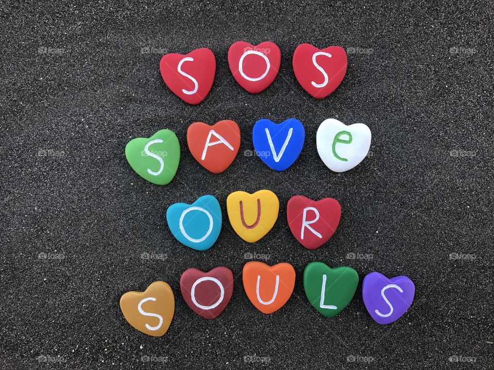 SOS, Save Our Souls, International Morse code distress signal with multicolored heart stones over black volcanic sand