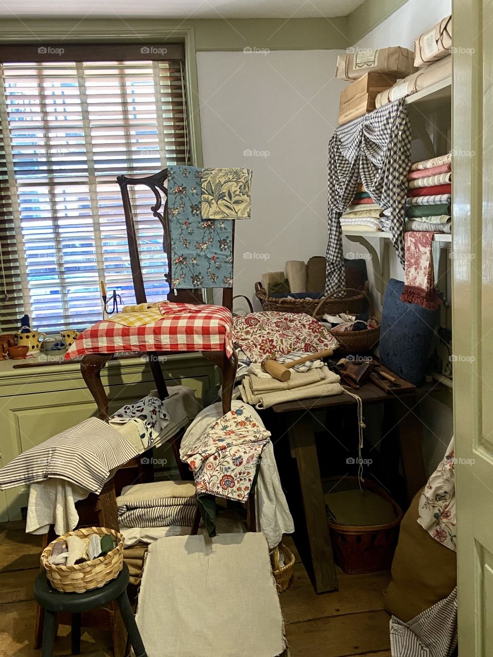 A room full of various fabrics used for sewing and home decor with a window in the back