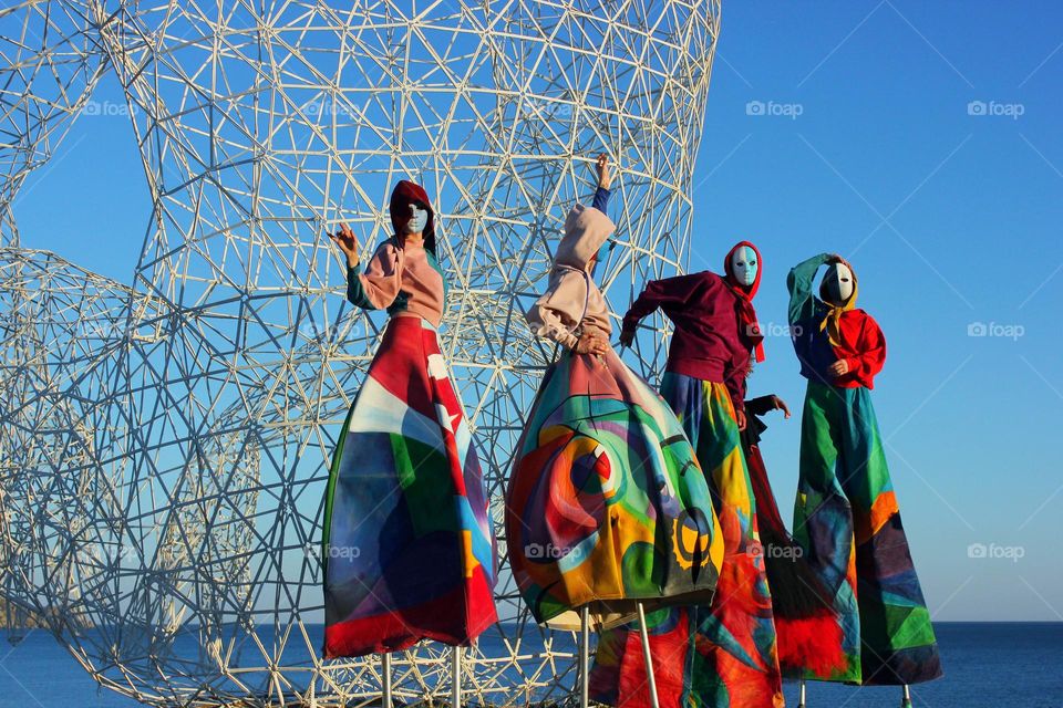 people people in masks and carnival costumes dance near metal structures