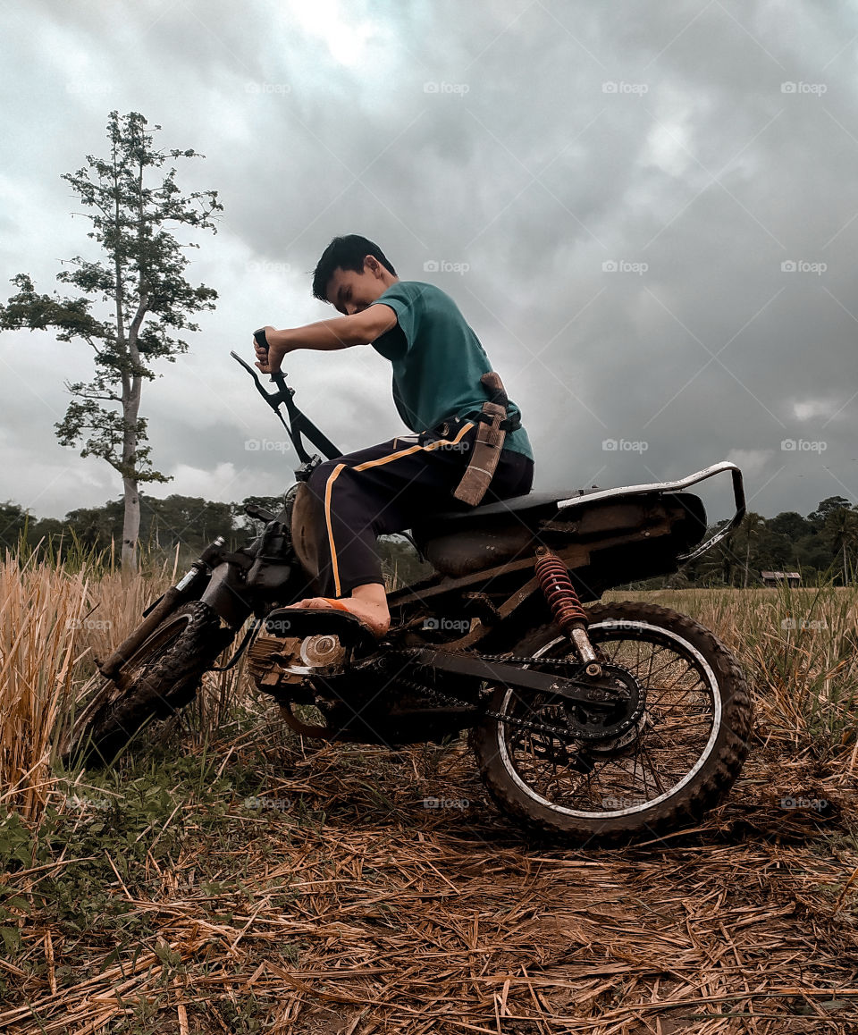 Bengkulu, Indonesia - March 10th, 2021 - a young man playing motorbikes in the middle of sawa