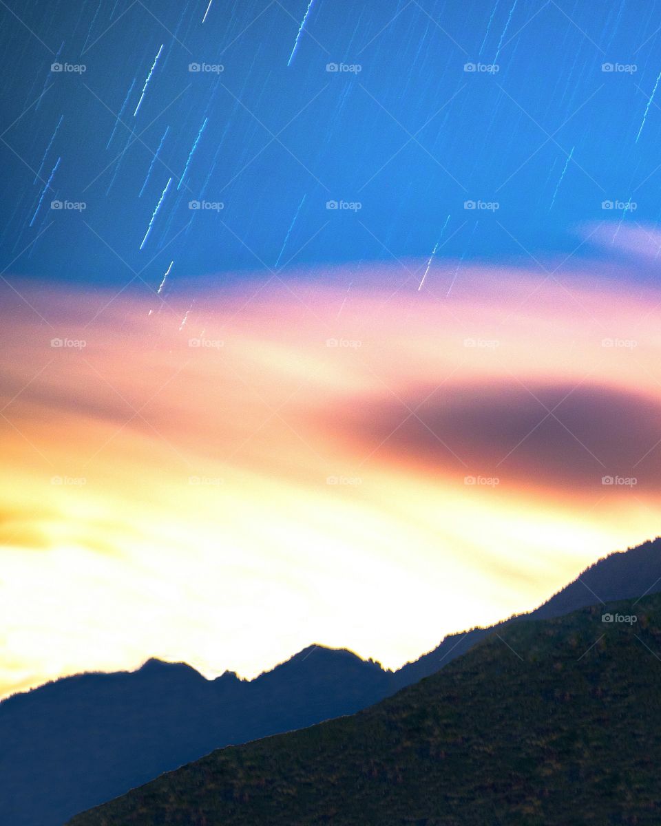 Star trails over mountains and clouds. imaginary,