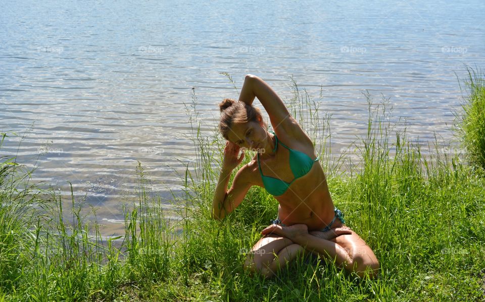 brunette girl in swimsuit training yoga lotus outdoor, summer time, lake shore