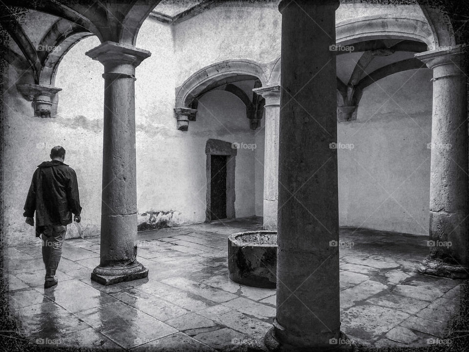 A lone person walks through the washing cloister at The Convent of Christ, Tomar, Portugal