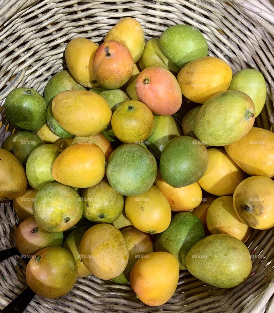 Baby mangoes or mangos inside a basket on sale at fruit market 