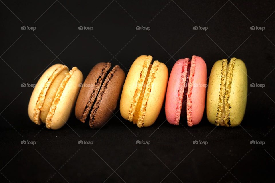 Multicolored macarons on the black background