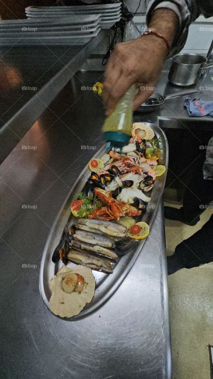 Hechando haciete de oliva virgen extra a la Mariscada