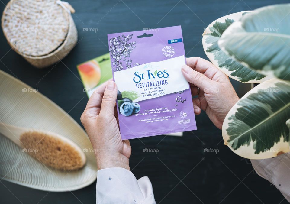 Woman with sheet mask St. Ives in hands at home 