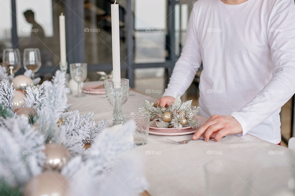 man sets a beautiful decorated winter table for a festive dinner.  Merry Christmas and Happy New Year.