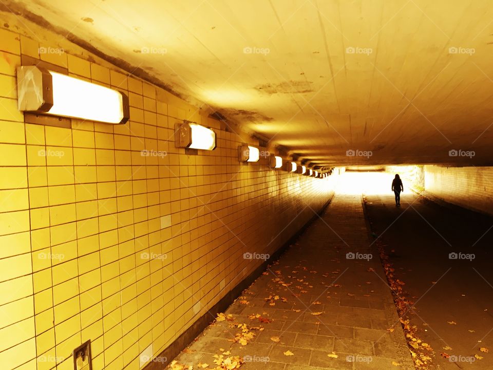 Human walking throw yellow underground tunnel a day in autumn. 