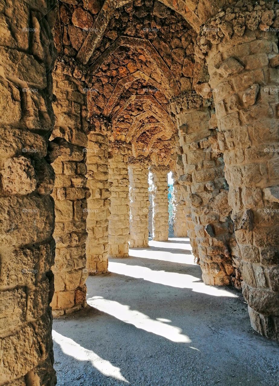 Light and shadow play under stone pillars at Guell park in Barcelona, Spain