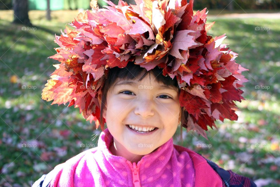 Happy smiling girl in autumn leaves wreath