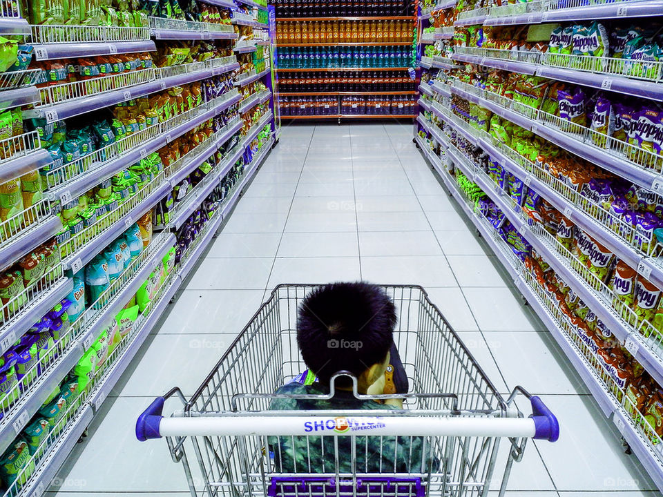 child riding a grocery cart in a grocery store