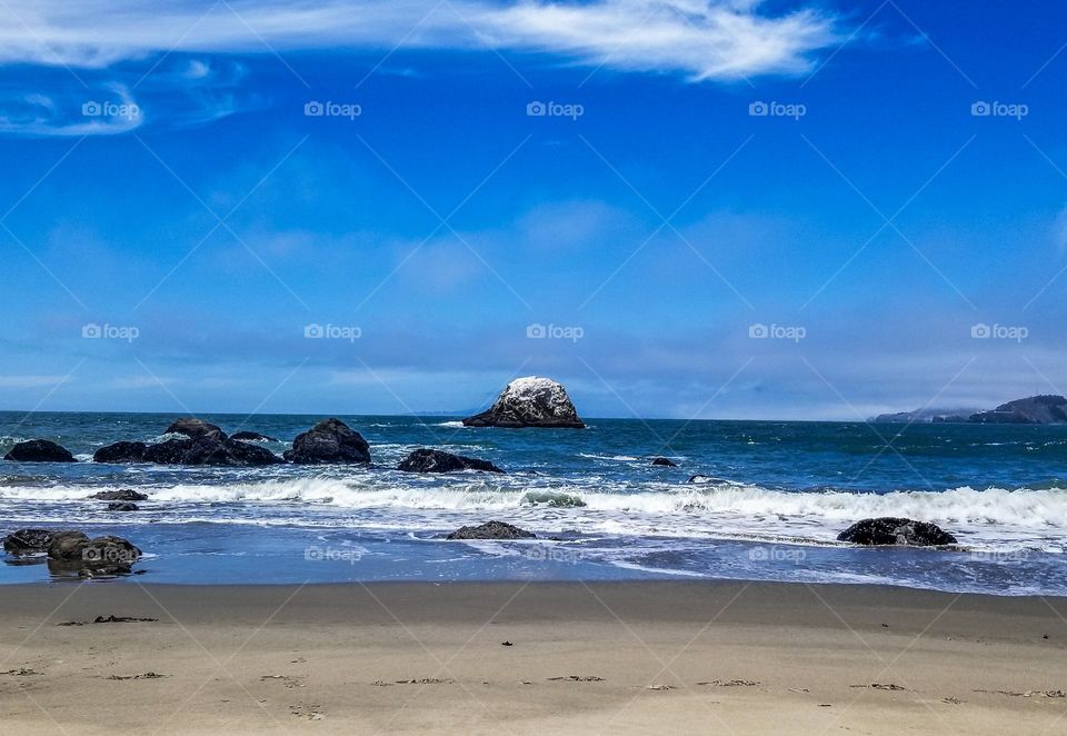 Rock formations off the coast of the Pacific Ocean from lands end beach in San Francisco, lovely sand and water with blue sky 