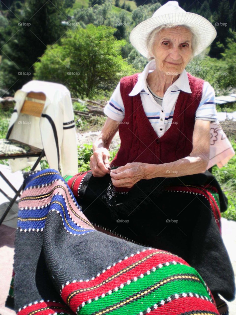 An old woman sewing a rug