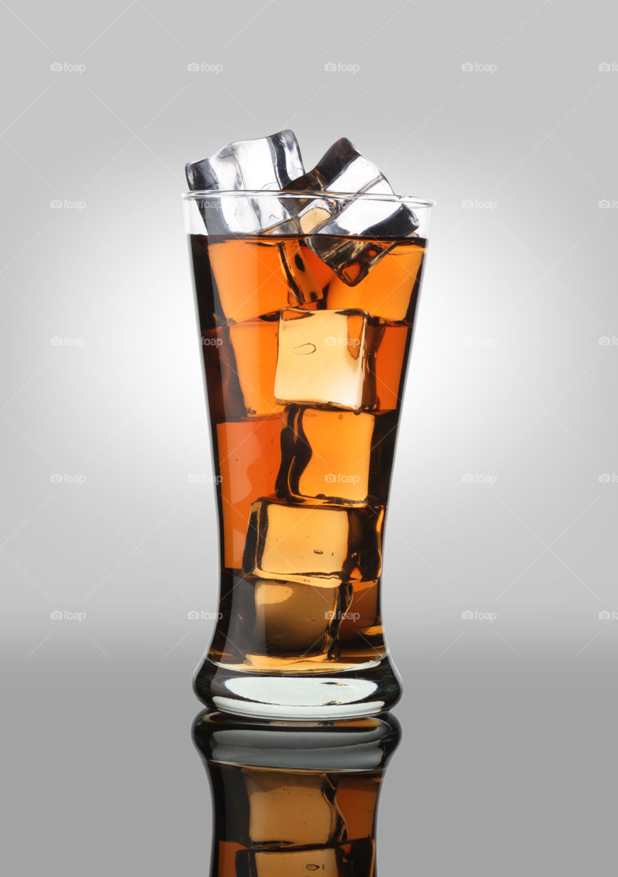 Cold drink cola soft drink in a glass with ice cubes