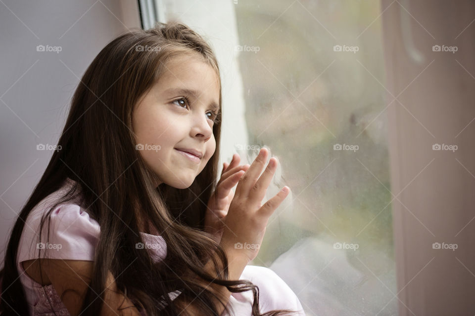 Smiling cute girl sitting near window