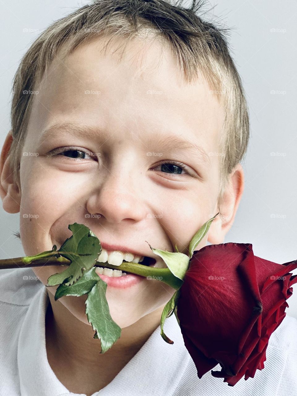 smiling boy with a rose in his mouth