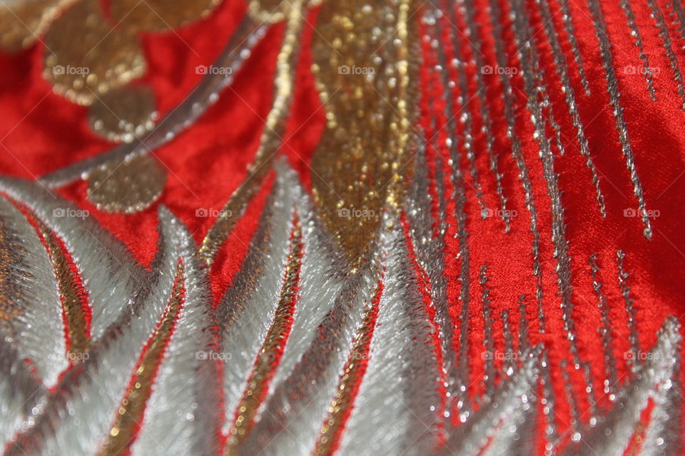 Closeup of a red fabric bag embellished with gold and silver embroidery and quilted designs. 